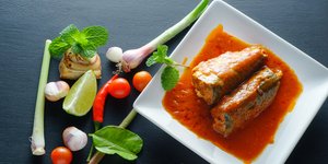 Κομμάτια ψάρι σε πιάτο με κόκκινη σάλτσα και λαχανικά