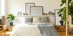 Μοντέρνο υπνοδωμάτιο με ράφια στον τοίχο, φυτά και ριχτάρια στο κρεβάτι