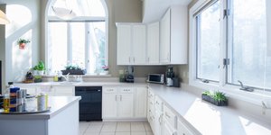 Κουζίνα με λευκά ντουλάπια, ηλεκτρικές συσκευές, παράθυρα, πλακάκια