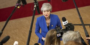 Η Τερέζα Μέι με μπλε σακάκι μπροστά σε δημοσιογράφους