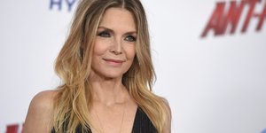 H Μισέλ Φάιφερ χαμογελάει στον φακό φορώντας μαύρο φόρεμα με ντεκολτέ