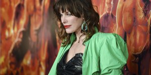 Η Μίλα Γιόβοβις με νέον πανωφόρι, μαύρο φόρεμα και πράσινο σκουλαρίκι 