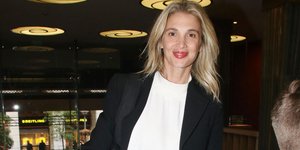 Η Νίκη Κάρτσωνα χαμογελάει στον φακό, φορώντας σακάκι και λευκή μπλούζα