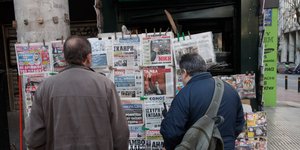 Άνδρες διαβάζουν πρωτοσέλιδα εφημερίδων