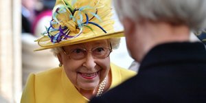 Η βασίλισσα Ελισάβετ με κίτρινο καπέλο και γυαλιά χαμογελάει