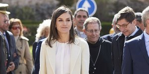 Η βασίλισσα Λετίθια με μπεζ παντελόνι και παλτό όρθια χαμογελάει