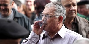 Ενας -σχετικά νέος- συνταξιούχων καπνίζει κατά τη διάρκεια συγκέντρωσης διαμαρτυρίας για τα αναδρομικά των συντάξεων στο κέντρο της Αθήνας