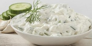Ενα μπολ τζατζίκι, με λίγα κομμένα αγγουράκια στο φόντο