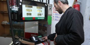 Υπάλληλος πρατηρίου καυσίμων καταχωρίζει συναλλαγή στην ταμειακή μηχανή, μπροστά από την αντλία καυσίμων