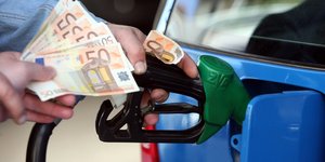 Οδηγός πληρώνει με χαρτονομίσματα ένα εργαζόμενο σε πρατήριο καυσίμων, την ώρα που εκείνος γεμίζει με καύσιμα ένα αυτοκίνητο