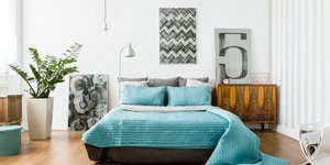 Στρωμένο κρεβάτι σε υπνοδωμάτιο διακοσμημένο με πίνακες και φυτά