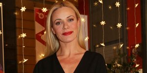 Η Ζέτα Μακρυπούλια με μαύρο φόρεμα και κόκκινο κραγιόν, χαμογελάει στον φακό