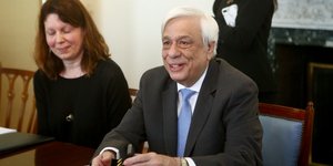 Προκόπης Παυλόπουλος κάθεται χαμογελαστός