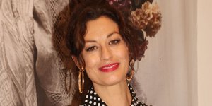 Η Δωροθέα Μερκούρη με πουά φόρεμα και λουλούδια ποζάρει χαμογελαστή