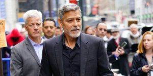Ο Τζορτζ Κλούνεϊ με μαύρο κοστούμι περπατάει στον δρόμο
