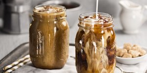 Δύο γυάλινα βάζα με παγωμένο καφέ πάνω σε έναν δίσκο με κουτάλι