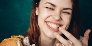 Γυναίκα χαμογελάει επειδή τρώει γευστικό μπέργκερ