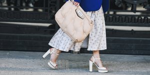 Γυναίκα περπατάει κρατώντας τσάντα, φοράει λευκές πλατφόρμες και μπλε σακάκι