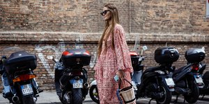 Γυναίκα με φόρεμα-καφτάνι και τσάντα περπατά στο δρόμο