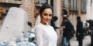 Γυναίκα με μαύρα μαλλιά, κόκκινη τσάντα, λευκό φόρεμα και λευκά παπούτσια