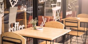 Τραπέζι έξω από καφέ με τζαμαρία και γράμματα