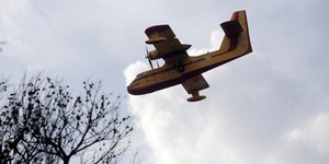 Eνα πυροσβεστικό αεροσκάφος Καναντέρ πετά πάνω από το Μάτι την επόμενη ημέρα της καταστροφής