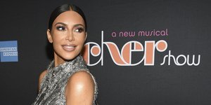 Η Κιμ Καρντάσιαν με ασημένιο φόρεμα, χαμογελάει και κοιτάει στο πλάι