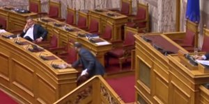 Η στιγμή που ο βουλευτής του ΚΚΕ αφήνει τη φωτογραφία στο έδρανο του Αλέξη Τσίπρα