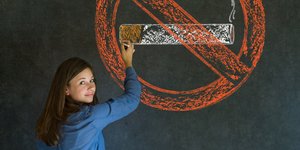 Κοπέλα ζωγραφίζει το απαγορευτικό κατά του καπνίσματος σε πίνακα