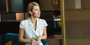 H Mαρία Ηλιάκη κάθεται σε πολυθρόνα σταυροπόδι και φοράει φόρεμα