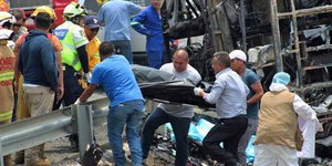 Διασώστες σε καμένο λεωφορείο βγάζουν πτώμα