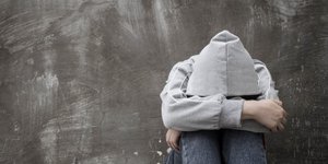 Χρήστης ναρκωτικών καθιστός στο πεζοδρόμιο με το κεφάλι ανάμεσα στα πόδια του