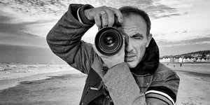 Ο Νίκος Αλιάγας κρατάει την φωτογραφική του μηχανή σε μια παραλία