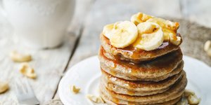Pancakes σε λευκό πιάτο με κομμάτια μπανάνας και μέλι