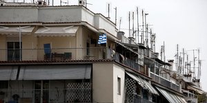 Εικόνα πολυκατοικίας στο κέντρο της Αθήνας με την ελληνική σημαία σε μπαλκόνι