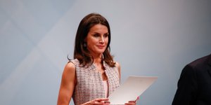 Η βασίλισσα Λετίθια με γιλέκο κρατάει χαρτιά και χαμογελάει