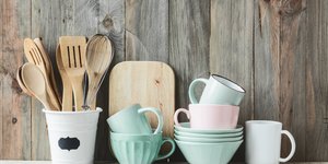 Πολύχρωμα ποτήρια και ξύλινα πιρούνια και σπάτουλες σε ράφι