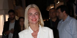 Η Χριστίνα Κοντοβά ντυμένη στα λευκά χαμογελάει στον φακό φορώντας κόκκινο κραγιόν
