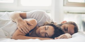 Ένας άνδρας και μια γυναίκα κοιμούνται αγκαλιά στο κρεβάτι