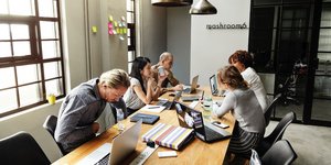 Ανδρες και γυναίκες σε γύρω από ένα μεγάλο τραπέζι εργάζονται