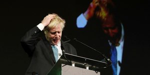 Ο Μπόρις Τζόνσον κρατάει το κεφάλι του κατά τη διάρκεια ομιλίας