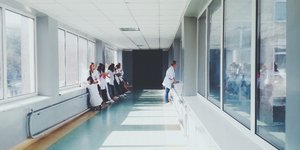 Διάδρομος νοσοκομείου με σχετικά λίγο κόσμο, παράθυρα από αριστερά