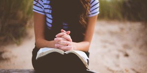 Καθισμένη γυναίκα σε παγκάκι κρατάει ένα βιβλίο στα πόδια της