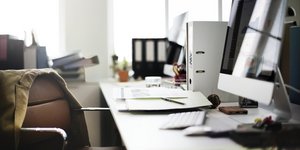 Γραφείο με άδεια καρέκλα, υπολογιστή και στο βάθος παράθυρα