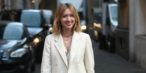 Γυναίκα χαμογελάει και φοράει εκρού ρούχα, παντελόνι με σακάκι