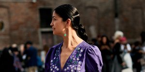 Γυναίκα με μωβ φόρεμα περπατά στο δρόμο