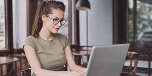 Γυναίκα με γυαλιά γράφει μπροστά στον υπολογιστή