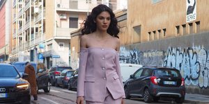 Μοντέλο περπατάει στο δρόμο με ροζ κοστούμι και τους ώμους έξω