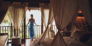 Μια γυναίκα με γαλάζιο φόρεμα σε ένα υπνοδωμάτιο με βεράντα 