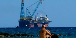 Ενας λουόμενος στην Κύπρο. Πίσω του μια πλατφόρμα εξόρυξης αερίου